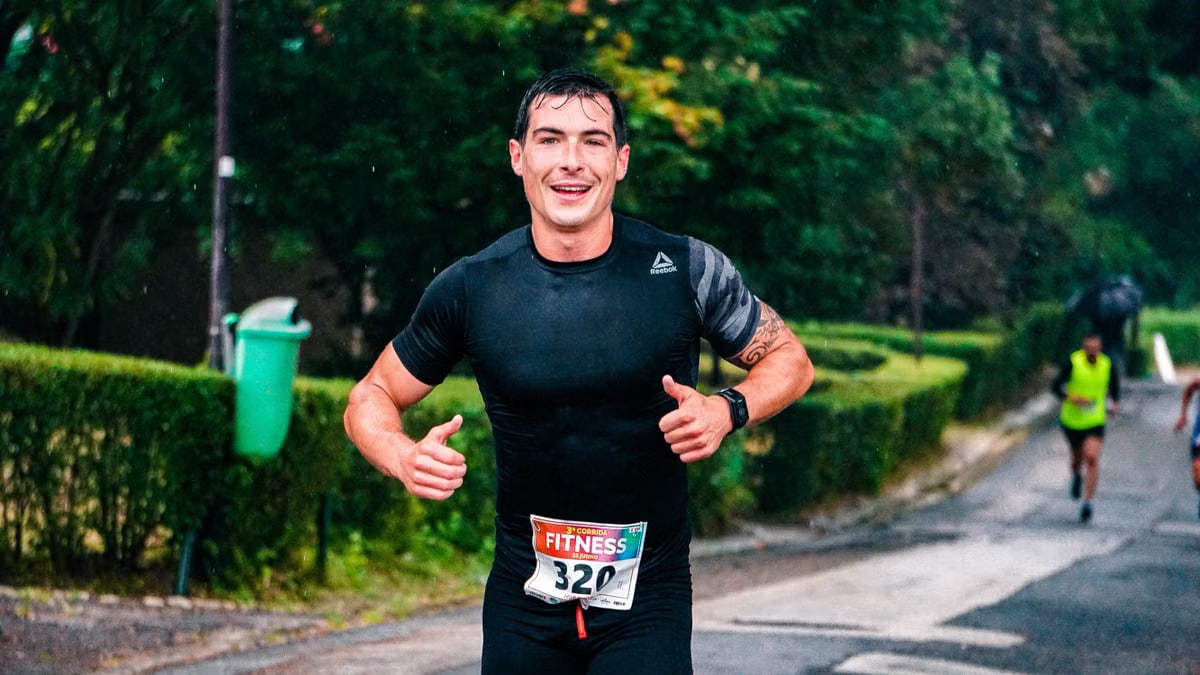 A fit male runner participating in an outdoor marathon during rainy conditions.